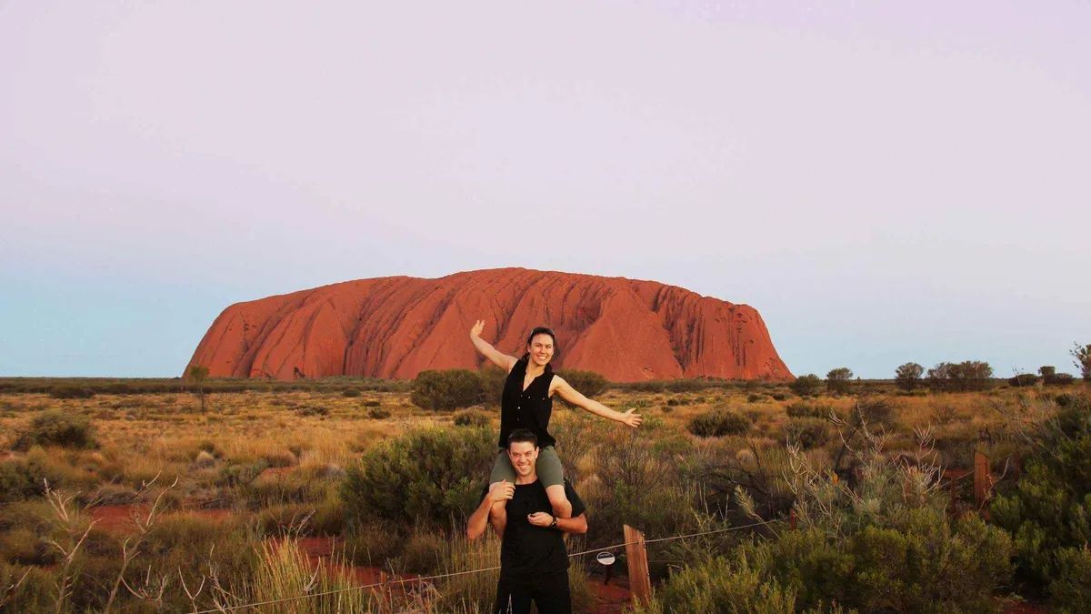 Coach travellers watching sunset colour on the rock during a day trip to Uluru from Alice Springs, Red Centre Australia
